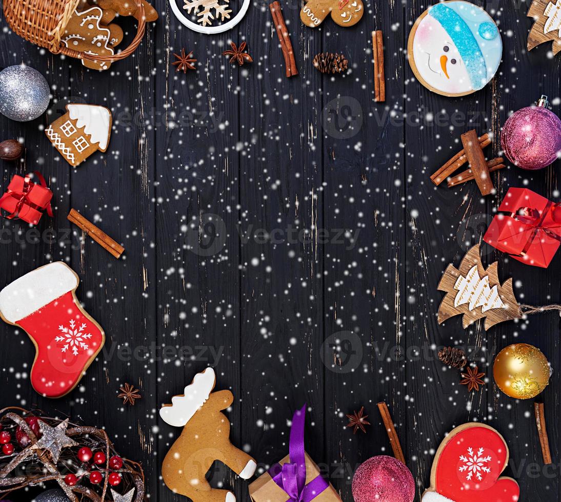 kerst achtergrond. kerstcadeau, speelgoed, peperkoekkoekjes, kruiden en decoraties op houten ondergrond. bovenaanzicht foto