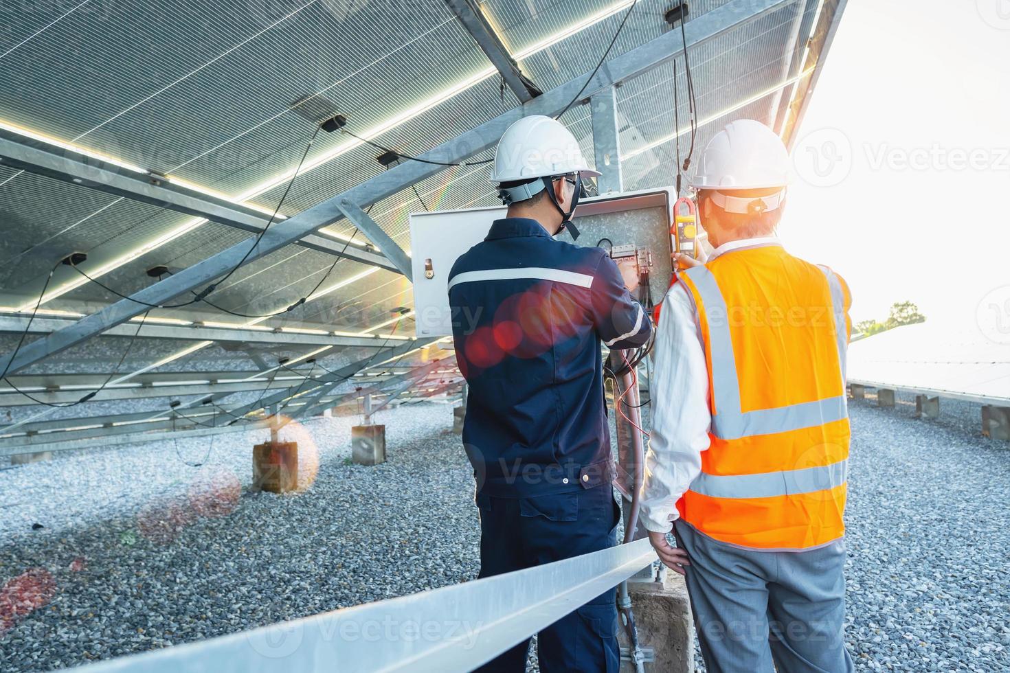 werknemers gebruiken stroomtang om de stroom van elektrische draden geproduceerd uit zonne-energie te meten voor bevestiging aan normale stroom foto