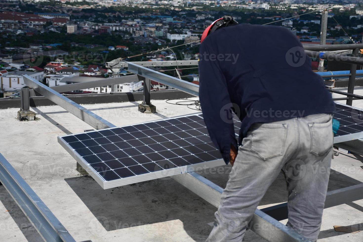 de monteur boort gaten om de zonnepaneelcel met elektrische boor op het dak te monteren. foto