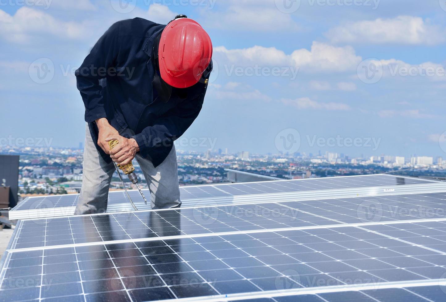 de monteur boort gaten om de zonnepaneelcel met elektrische boor op het dak te monteren. foto