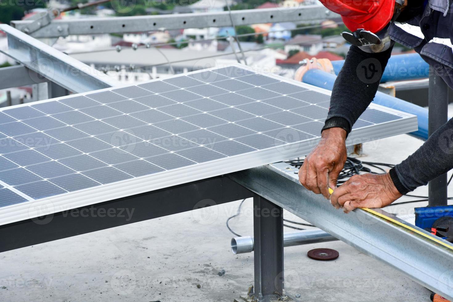 de monteur boort gaten om de zonnepaneelcel met elektrische boor op het dak te monteren. foto