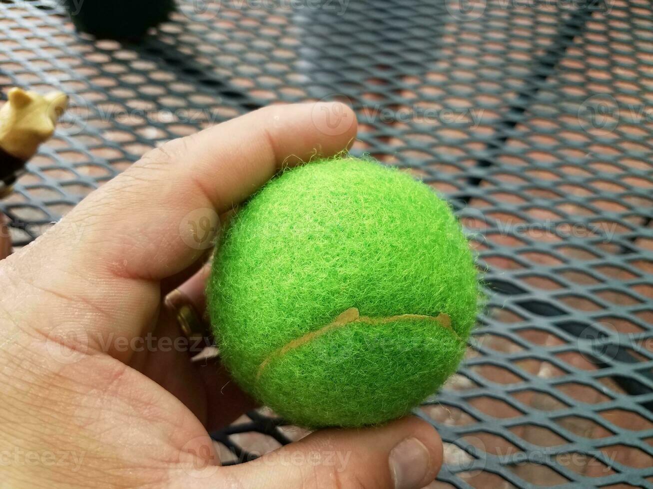 hand met groene tennisbal over metalen tafel foto