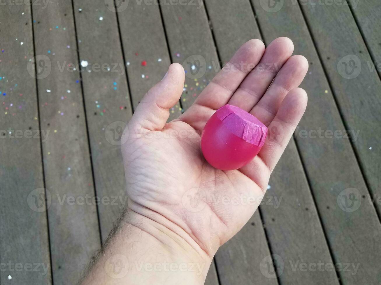 hand met roze eierschaal met confetti op houten dek foto