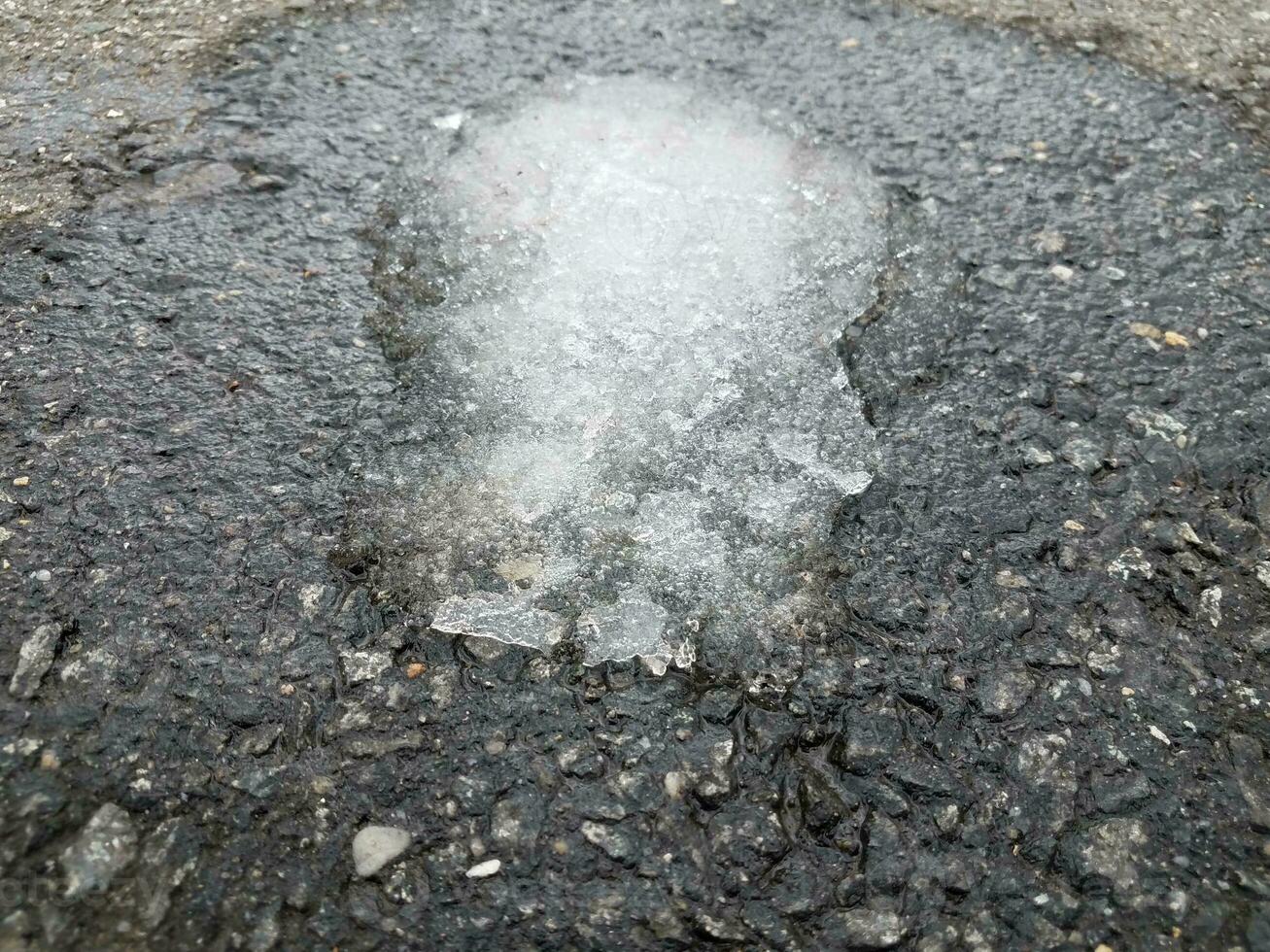 ijs smelten op zwart asfalt of bestrating foto