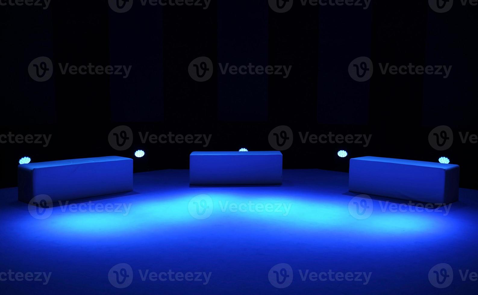 drie stoelen en blauwe verlichting op het podium foto