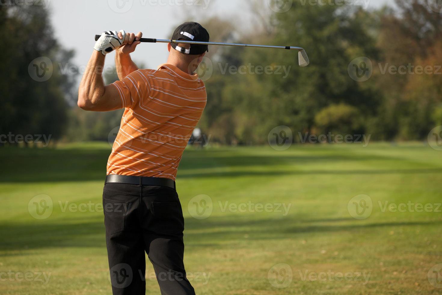 jonge man swingende golfclub, achteraanzicht foto