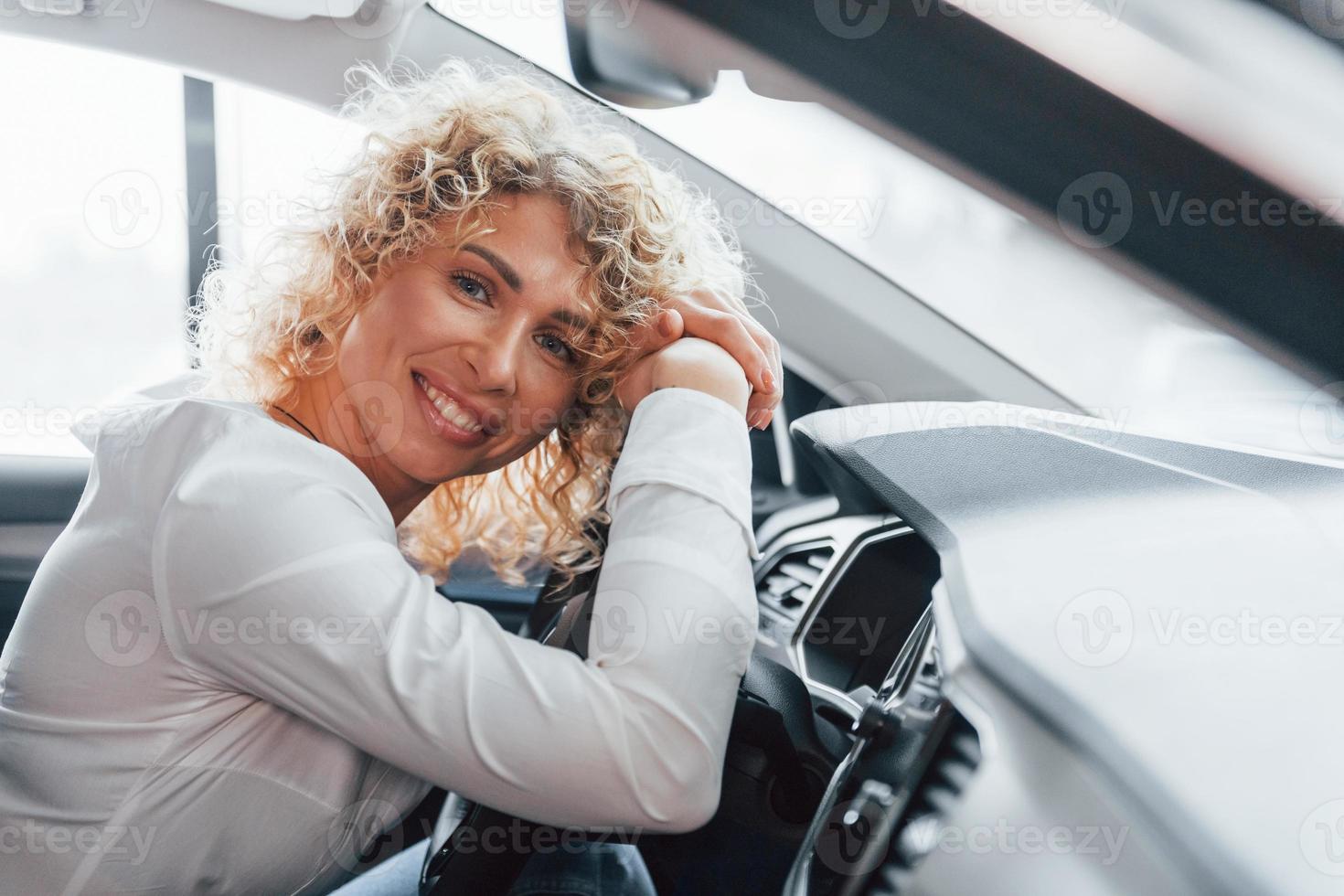 interieur van het voertuig. vrouw met krullend blond haar is in autosalon foto