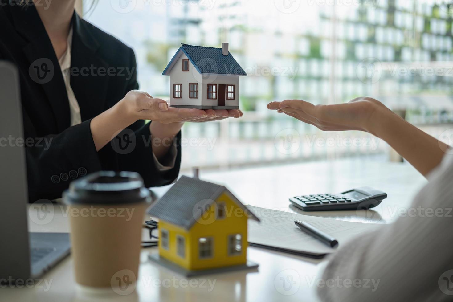 huizen en grond kopen, garanties, contract en overeenkomst, een medewerker van een vastgoedbedrijf overhandigt het huis en de sleutels nadat het contract voor de verkoop van grond en gebouwen is voltooid. foto