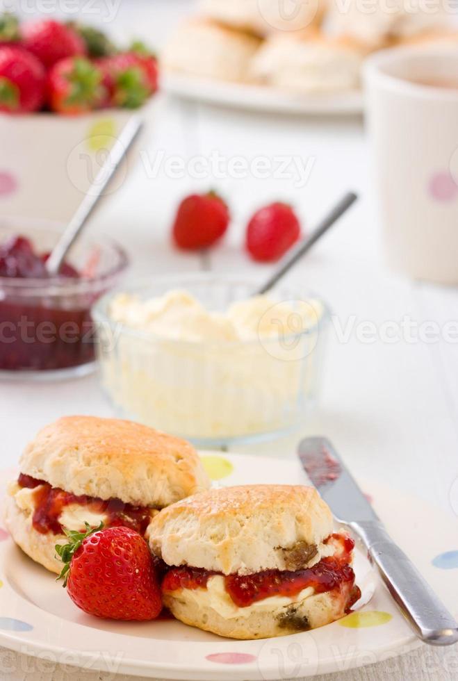 zelfgebakken scones aardbeienjam, aardbeien met clotted cream en thee. foto