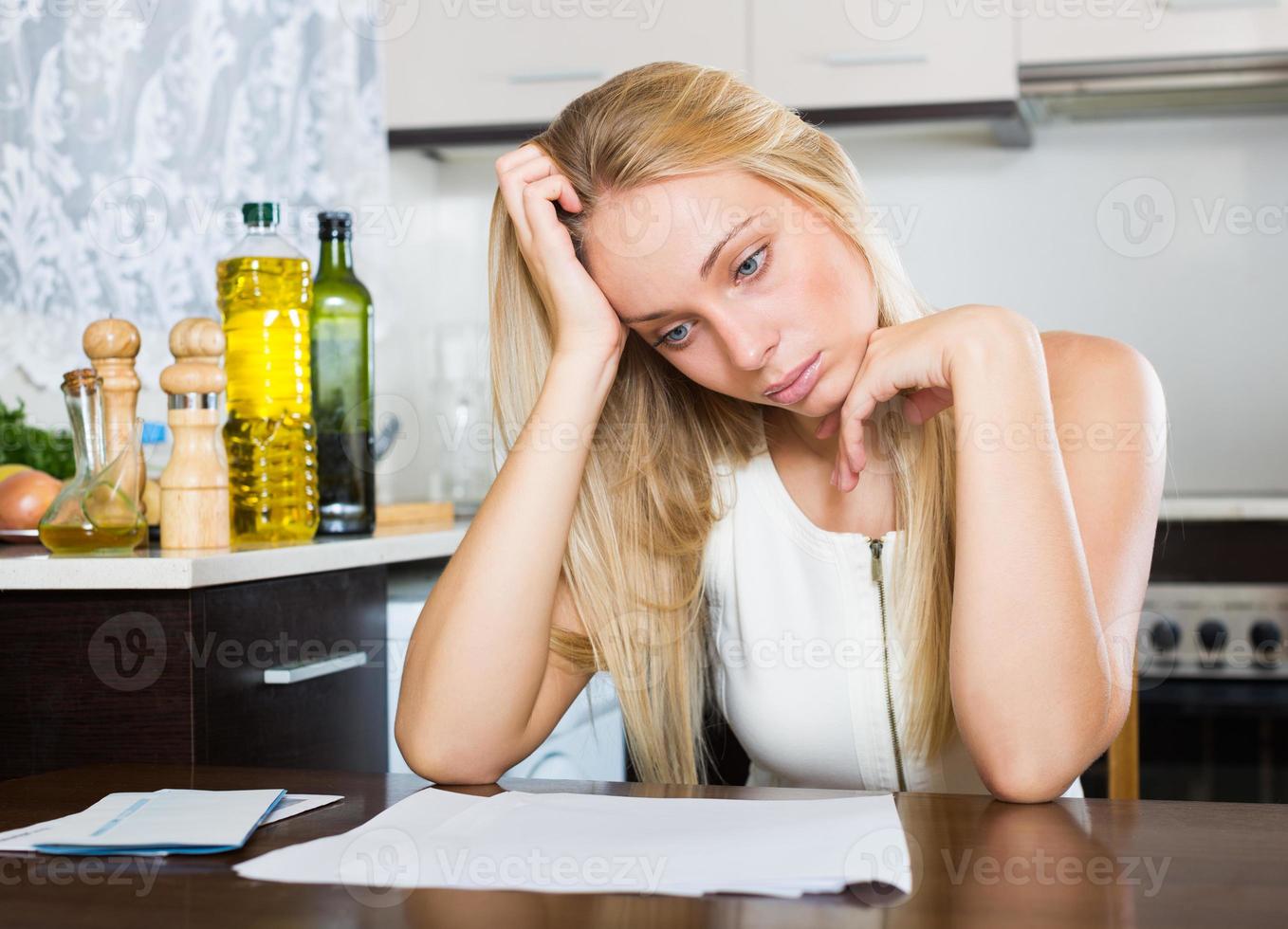 triest blonde vrouw met financiële documenten foto