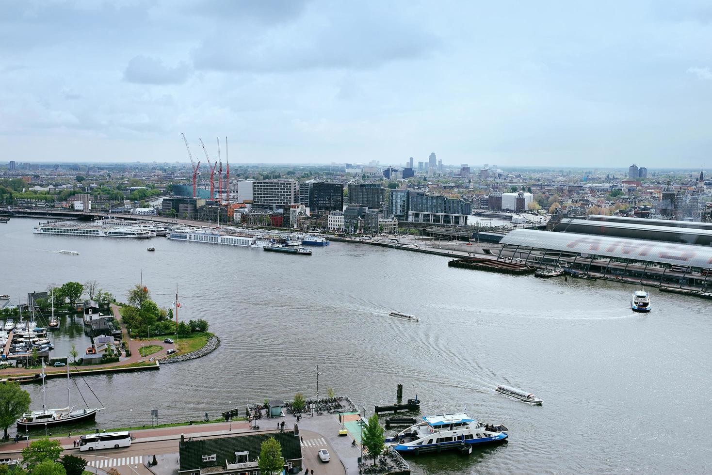 Amsterdam, Nederland - 28 april 2019 uitzicht op de stad naar het centrale deel van de stad, de veerboot en het kanaal van bovenaf in bewolkte typisch Nederlandse dag. foto