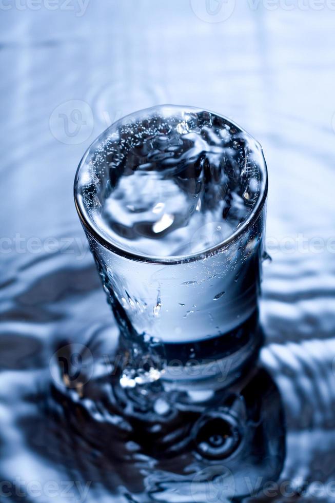 blauw zwart-wit beeld van water dat in een glas spettert. foto