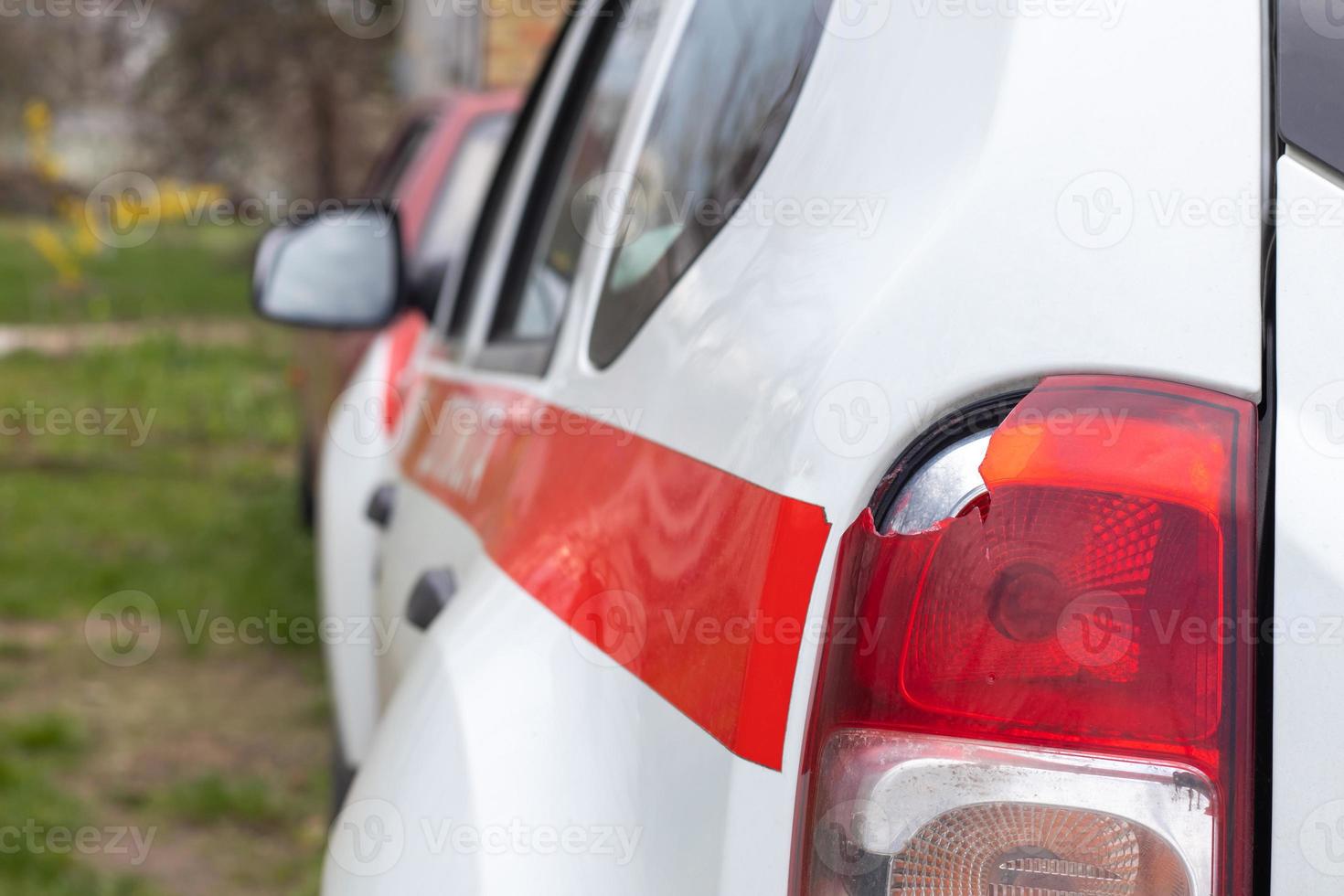 het linker achterlicht van een witte auto is kapot. het achterlicht van de auto werd verbrijzeld bij het ongeval. schade ongeval. veiligheidsconcept. achter stop van een auto in een close-up van een ongeval. foto