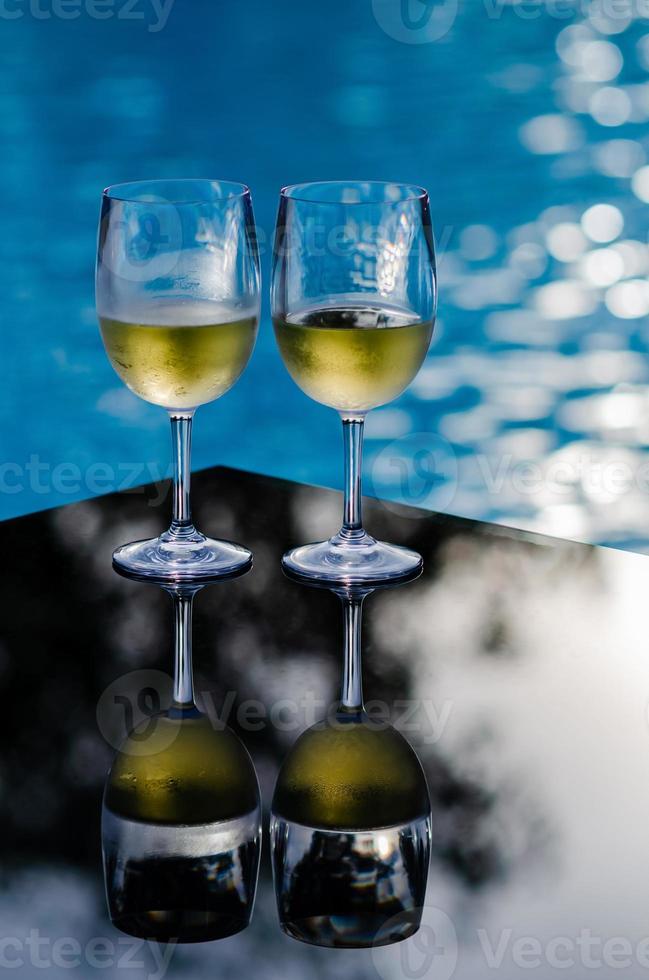twee glazen witte wijn op tafel bij het zwembad voor vakantie- en zomerdrankconcept. foto
