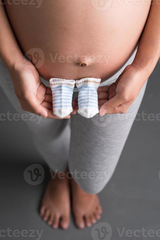 zwangere vrouw met kindersokken foto
