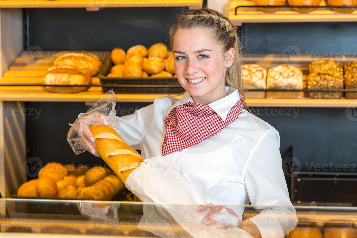 winkelier bij bakkerij zetten brood in papieren zak foto