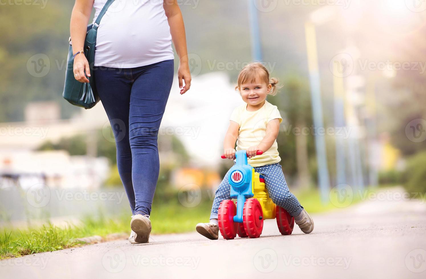 jonge zwangere moeder met dochtertje in park foto