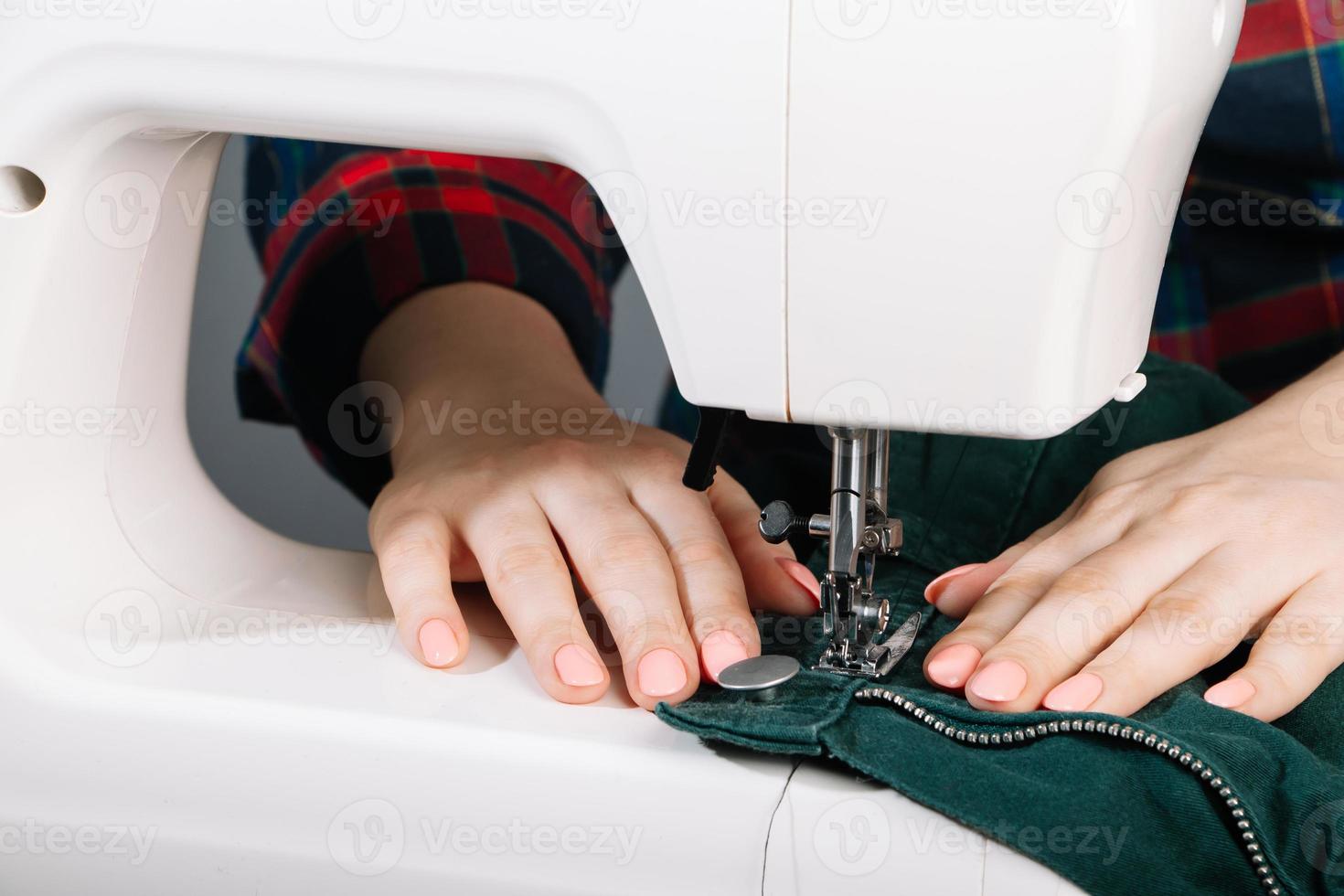 vrouw kleermaker werkt op naaimachine. wereld kleermakers dag. close-up van het naaiproces. foto