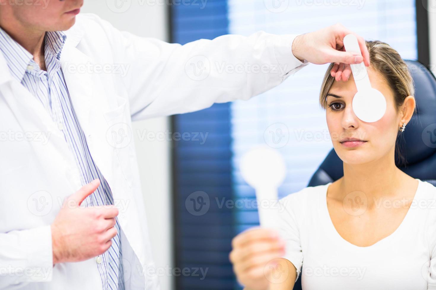 mooie jonge vrouw met haar ogen onderzocht door optometrie foto