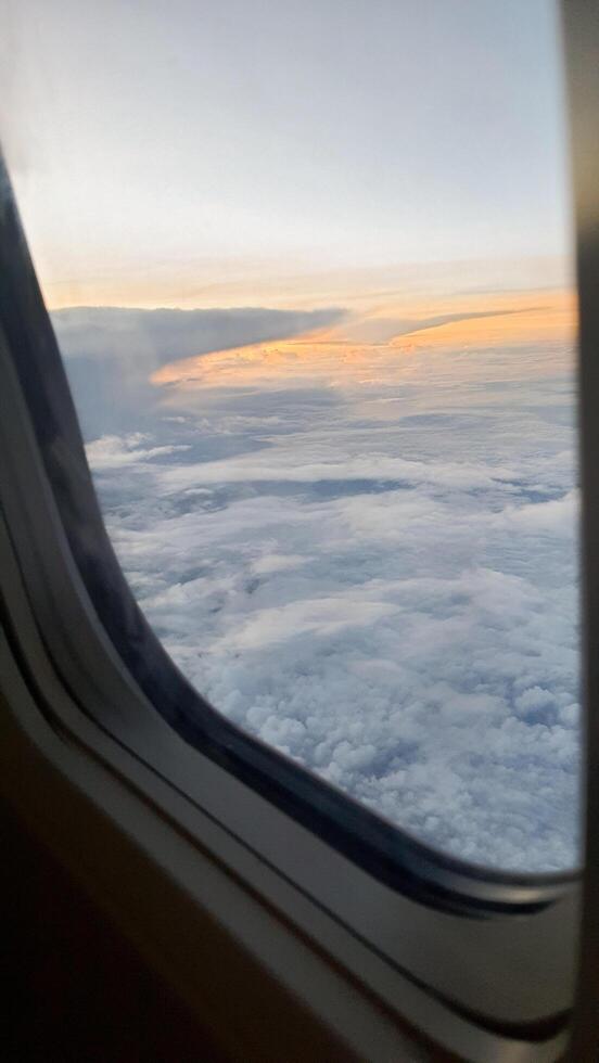 uitzicht vanuit het raam van het vliegtuig. de lucht met witte wolken en blauwe achtergrond. helder weer met een zonlicht dat zakt en de vleugels van het vliegtuig onthult foto