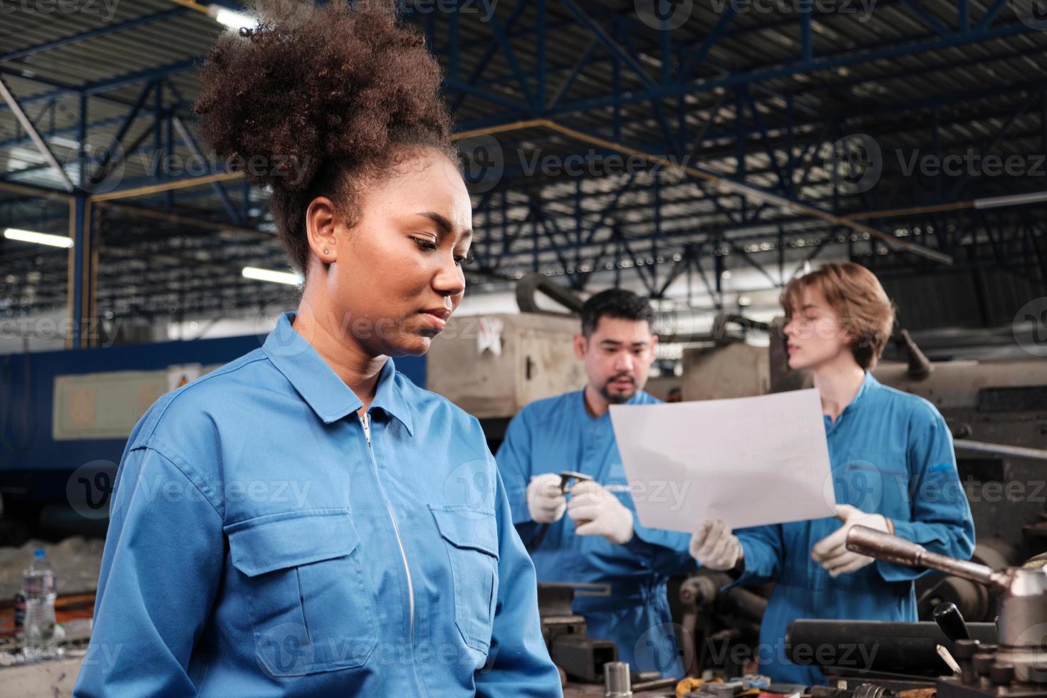 een professionele Afro-Amerikaanse vrouwelijke industrie-ingenieurswerknemer werkt in veiligheidsuniform met precisiegereedschappen voor metaalbewerking, mechanische draaimachines en werkplaats voor reserveonderdelen in een productiefabriek. foto