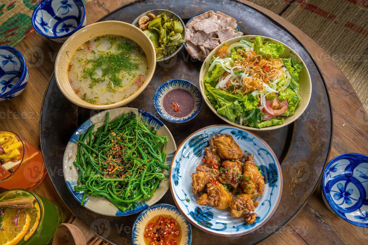 Vietnam familie thuiskok set voor vier personen gekookte rijst, groentesoep en gebakken vissen, gebakken uien met kip, komkommerschijfje, Vietnamese traditionele maaltijd op het platteland. foto