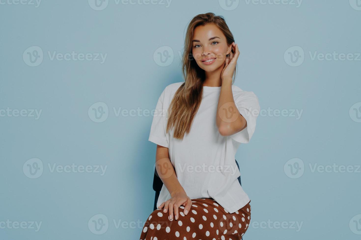 mooie brunette vrouw draagt witte casual t-shirt en rok poseren in studio foto