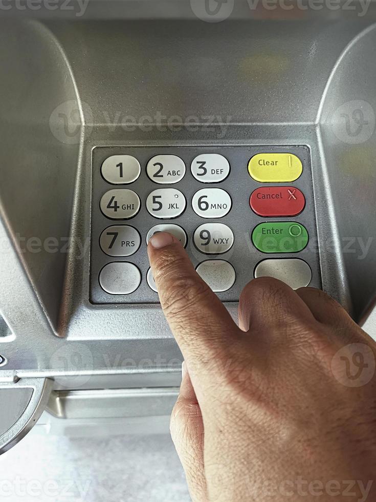 close-up van de hand die de pincode invoert op het toetsenbord van de bankautomaat foto