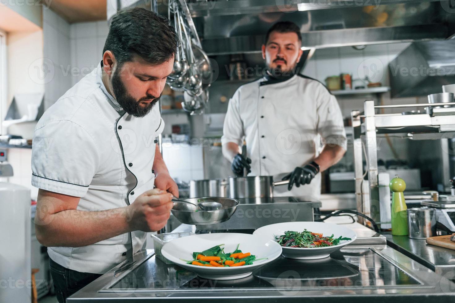 twee mannen maken salade. professionele chef-kok die voedsel in de keuken bereidt foto