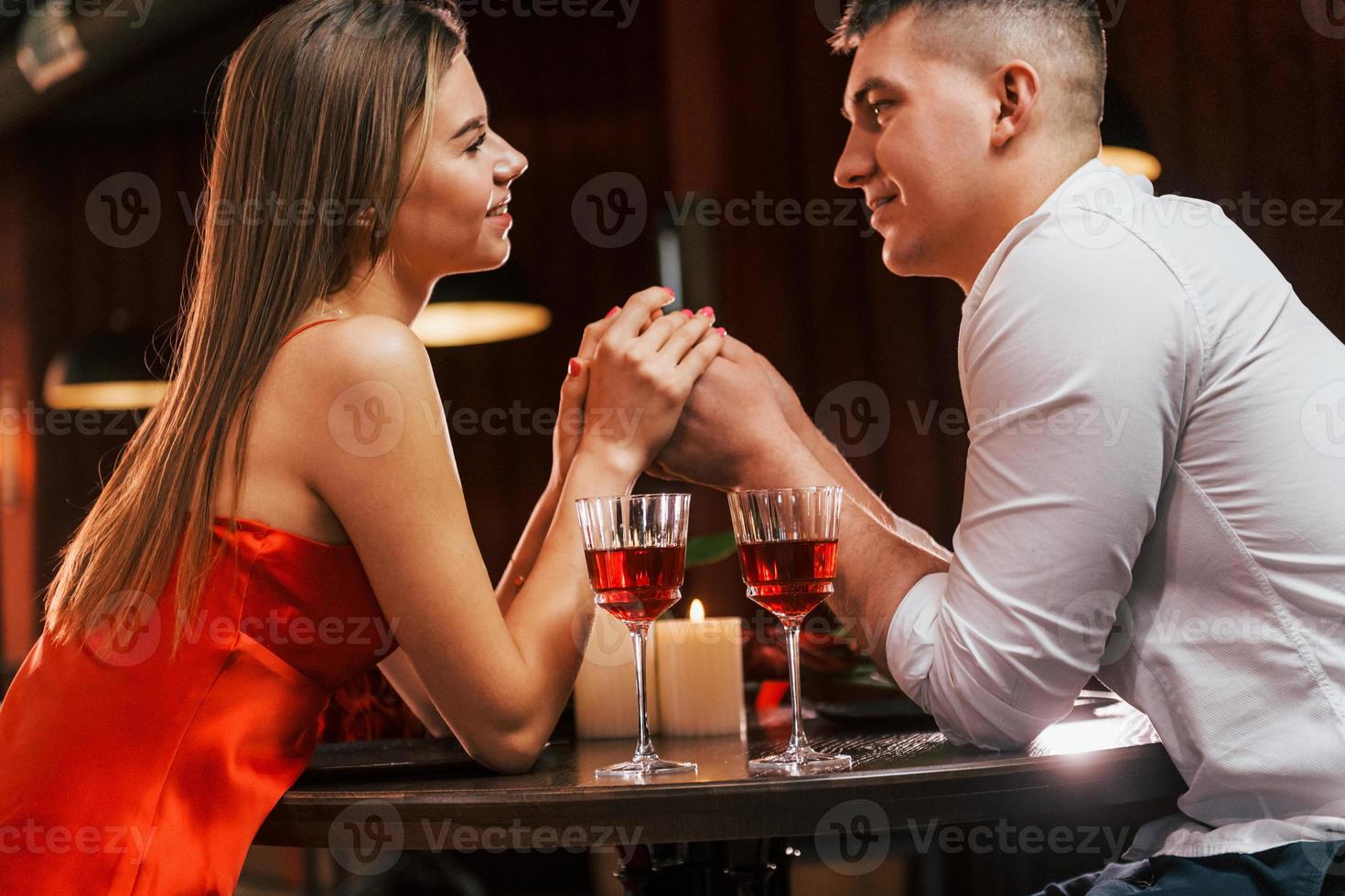 in rode jurk en wit overhemd. romantisch stel dineren in het restaurant foto