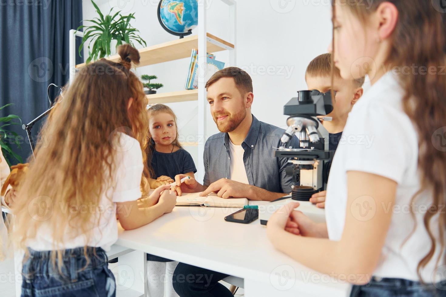 werken met de microscoop. groep kinderen studenten in de klas op school met leraar foto