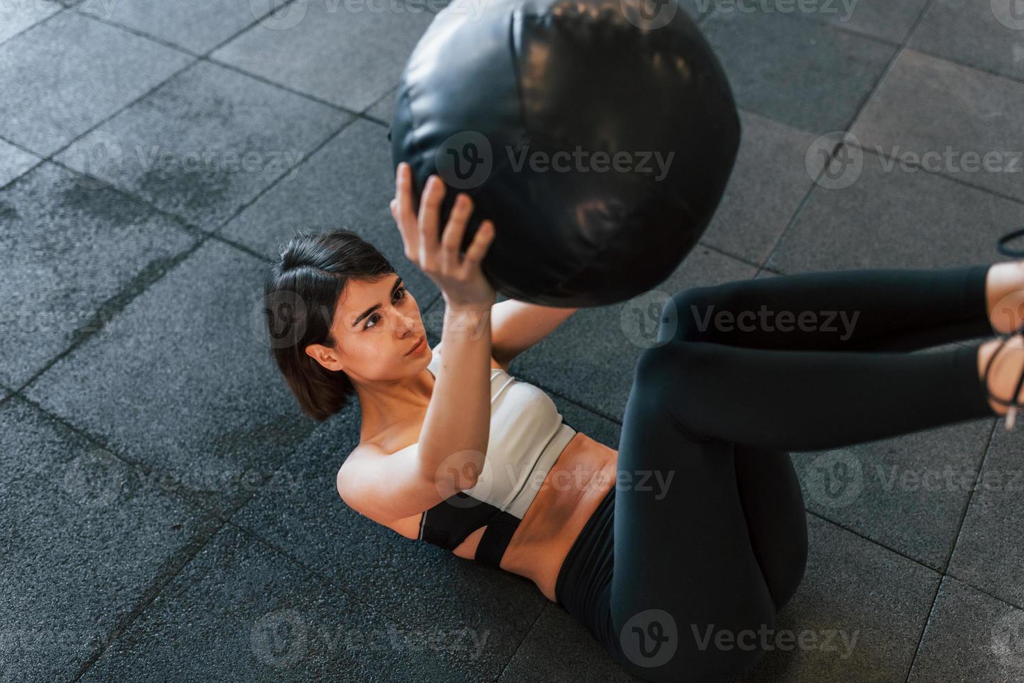 zwarte fitnessbal. vrouw in sportieve kleding met slank lichaamstype is in de sportschool foto