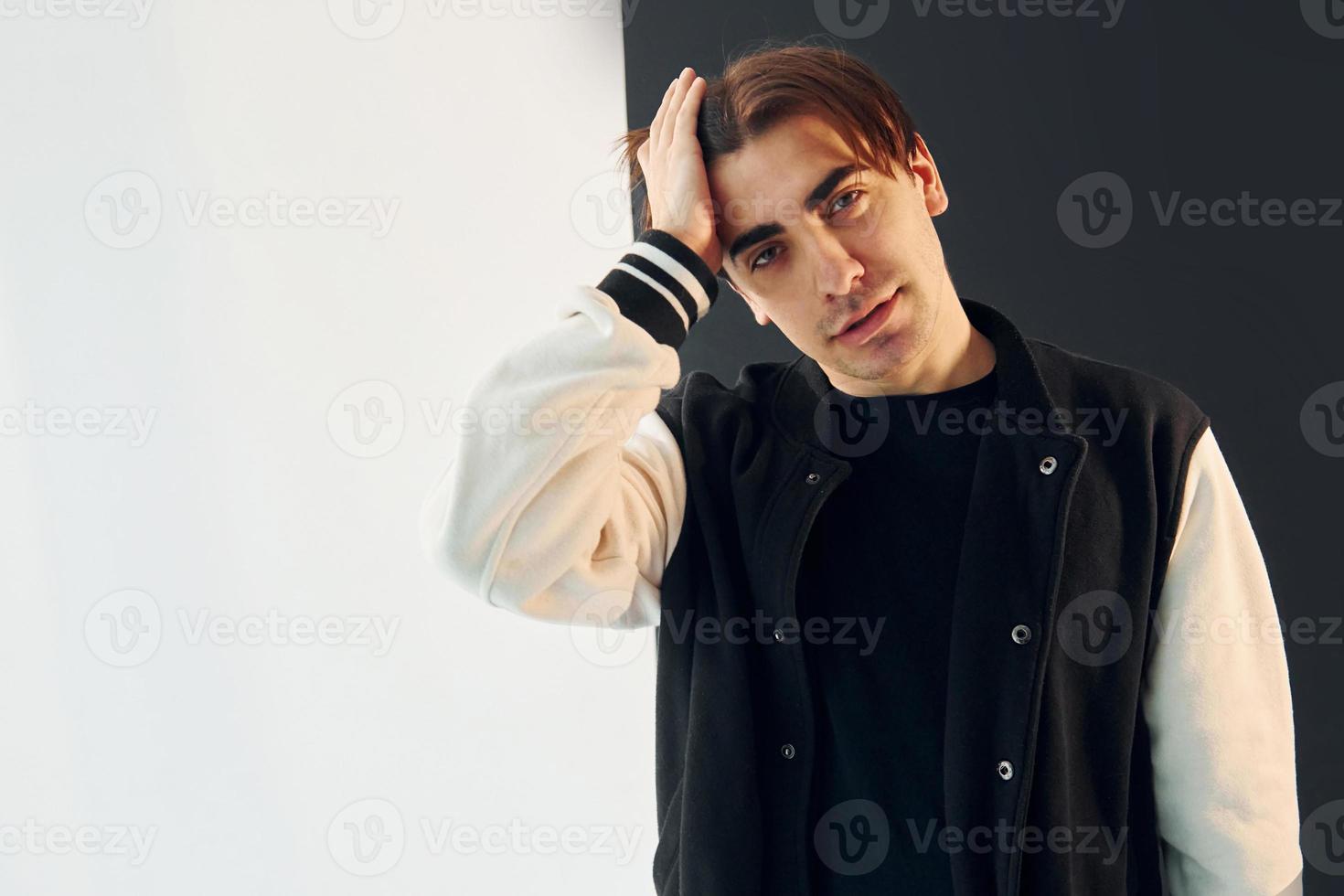 in de camera kijken. jonge man is in de studio met witte en zwarte muren foto