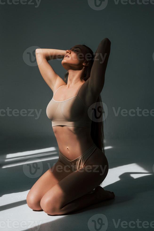 genietend van zonlicht. vrouw in ondergoed met slank lichaamstype poseert in de studio foto
