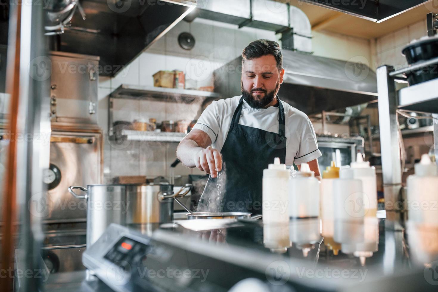 wat zout gieten. professionele chef-kok die voedsel in de keuken bereidt foto