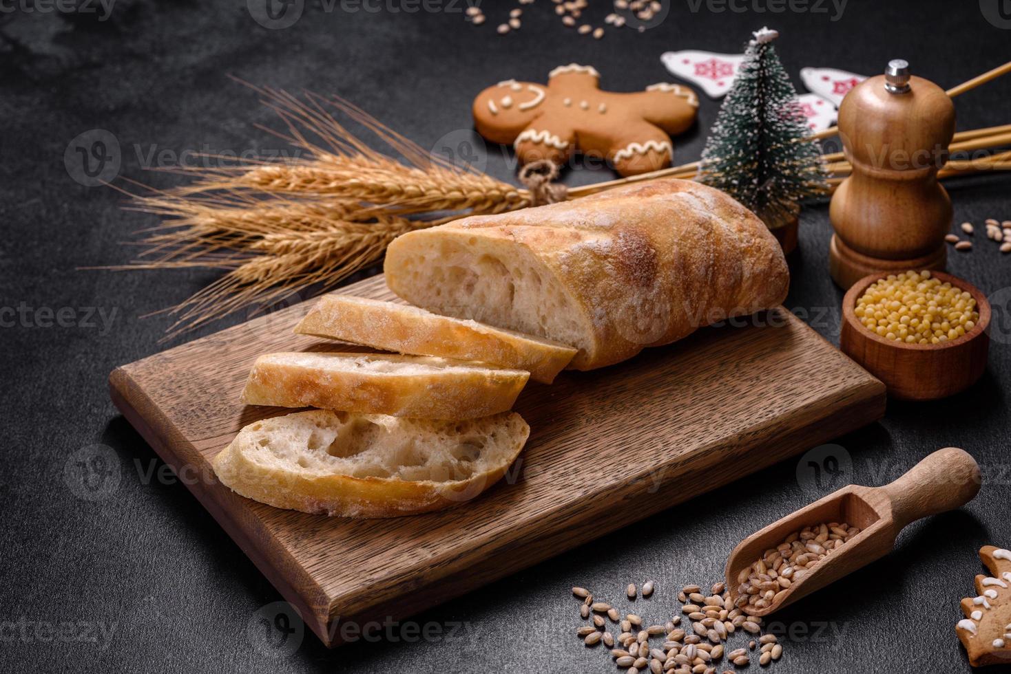 Frans stokbrood brood gesneden op een houten snijplank tegen een donkere betonnen achtergrond foto