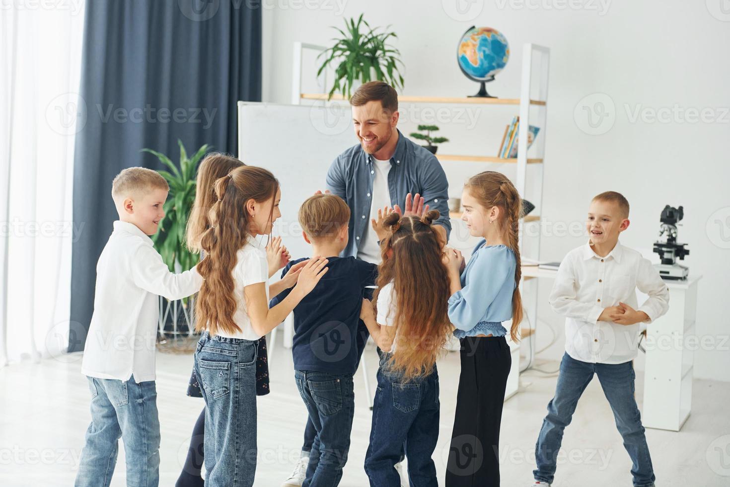 high fives gebaar. groep kinderen studenten in de klas op school met leraar foto