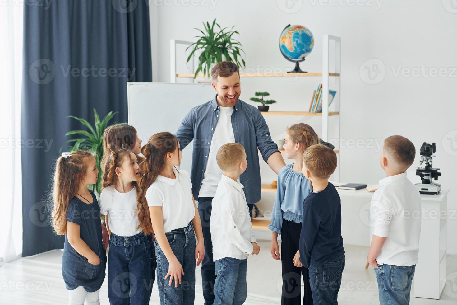 staan en high fives geven. groep kinderen studenten in de klas op school met leraar foto