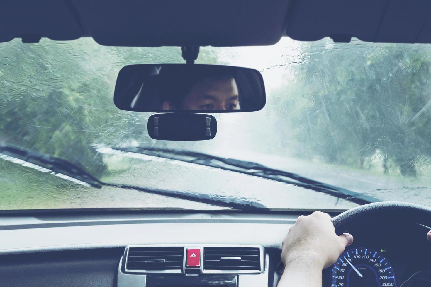 man rijdt auto bij hevige regenval foto