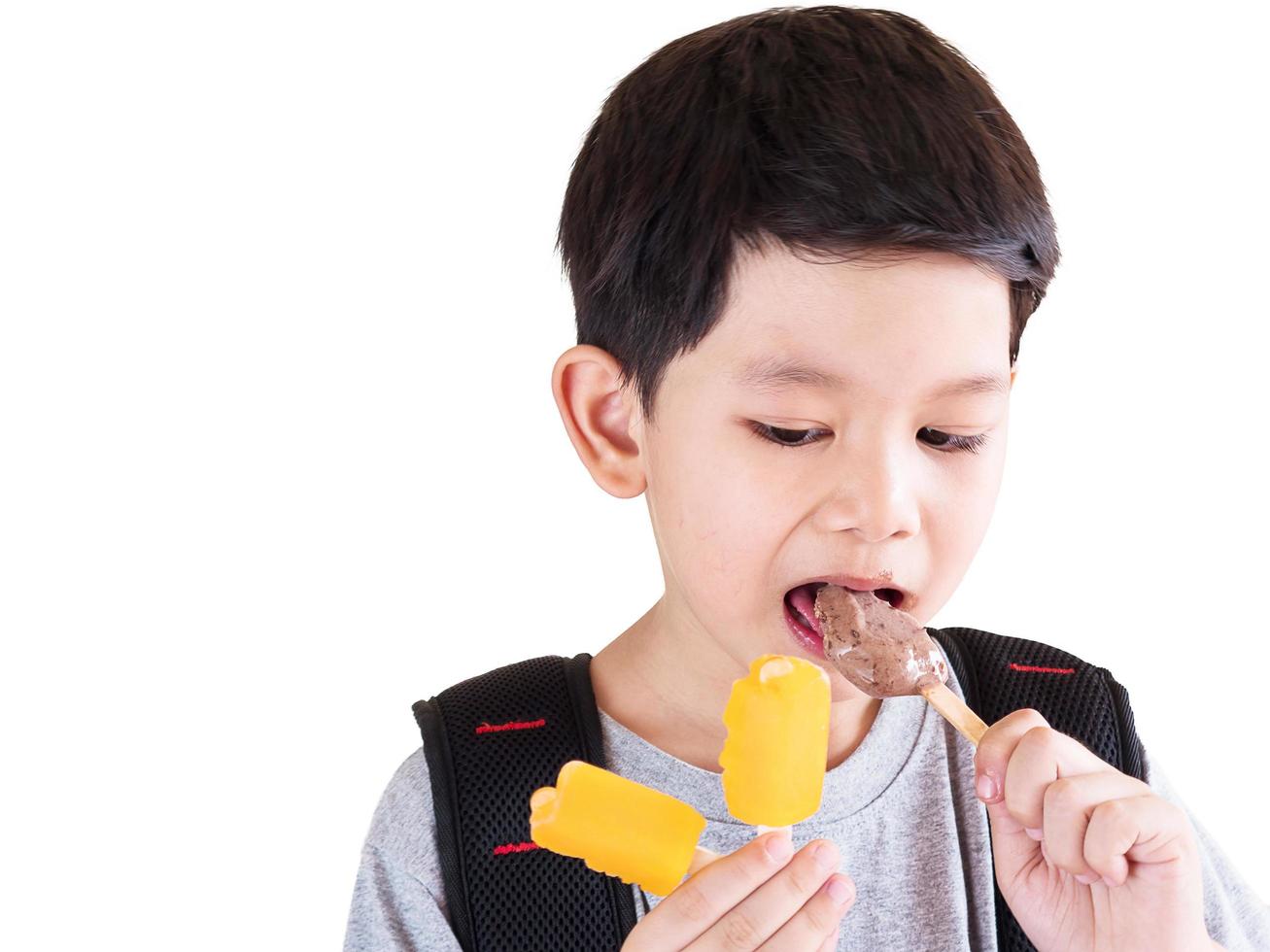 jongen die roomijs eet dat over witte achtergrond wordt geïsoleerd foto