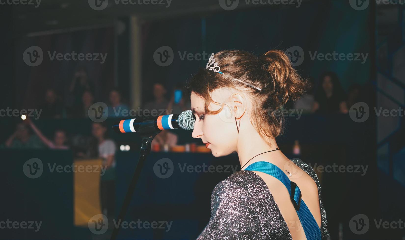 jonge blanke zangeres die een lied op een podium uitvoert. zingende vrouw, emotioneel gepassioneerde zangeres. rockmuziek openbaar concert. achteraanzicht foto