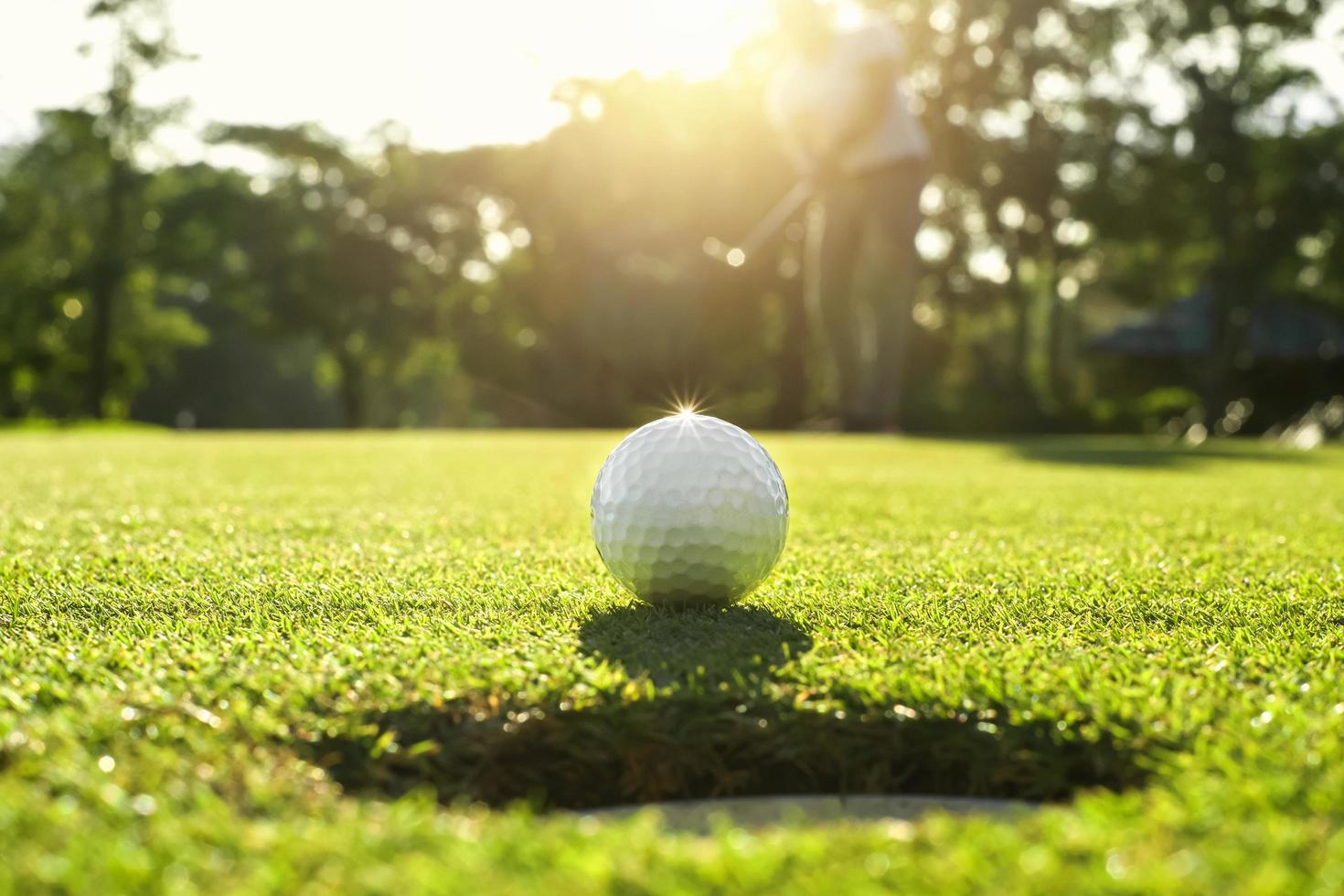 golfspeler die golfbal in gat zet foto