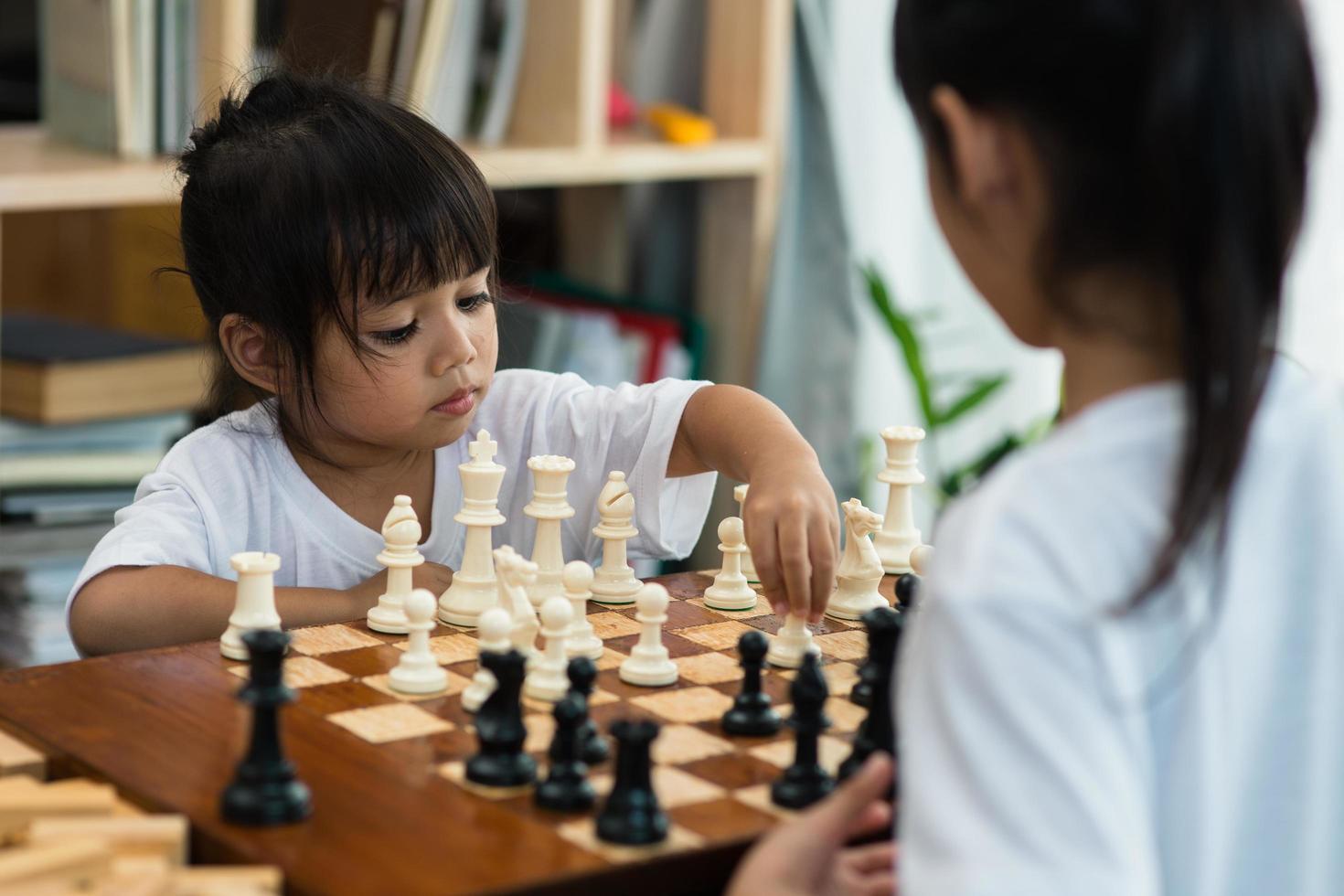 twee schattige kinderen die thuis schaken foto