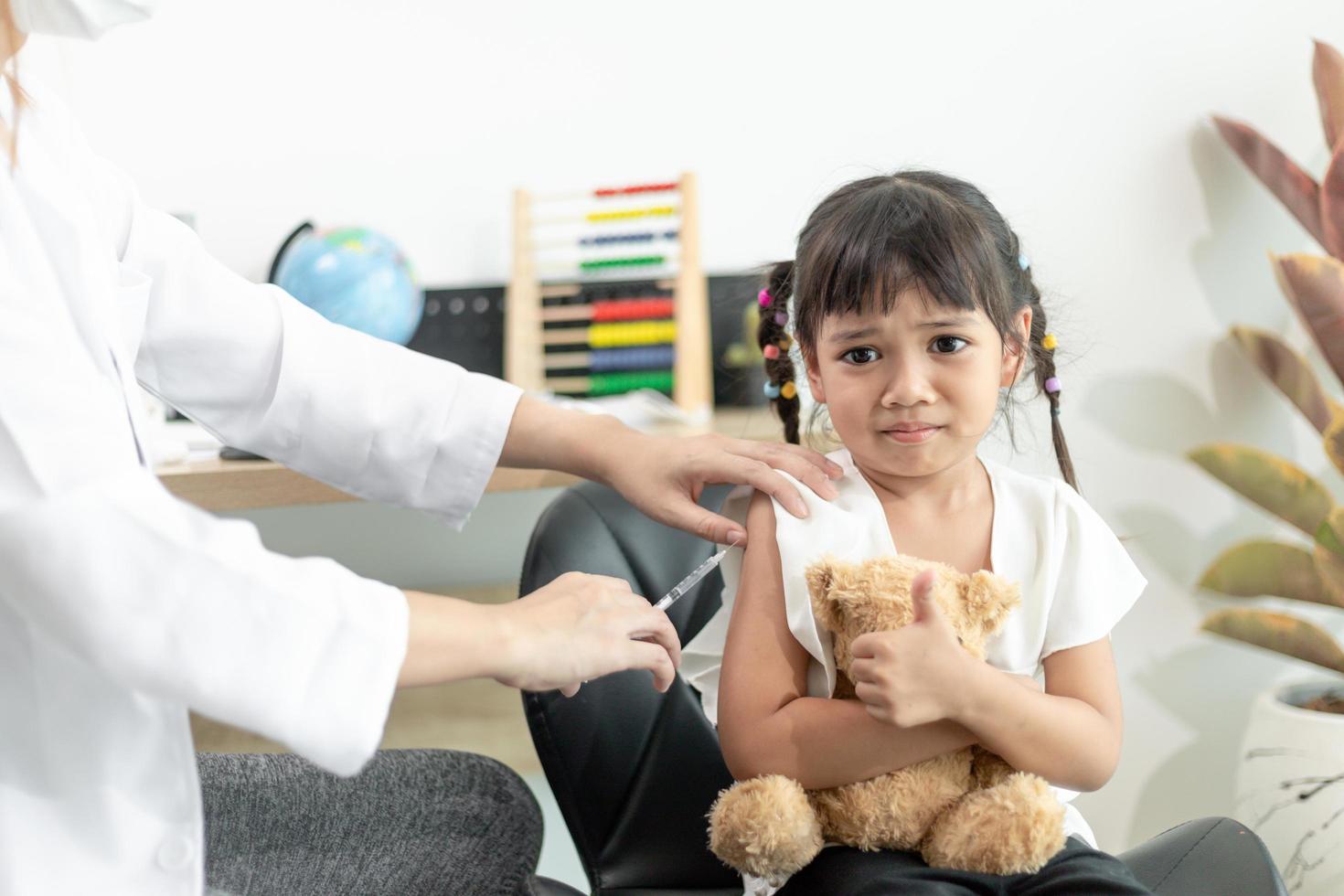 succesvolle covid-19-vaccinatie. schattig klein meisje terwijl ze wordt ingeënt tegen het coronavirus foto