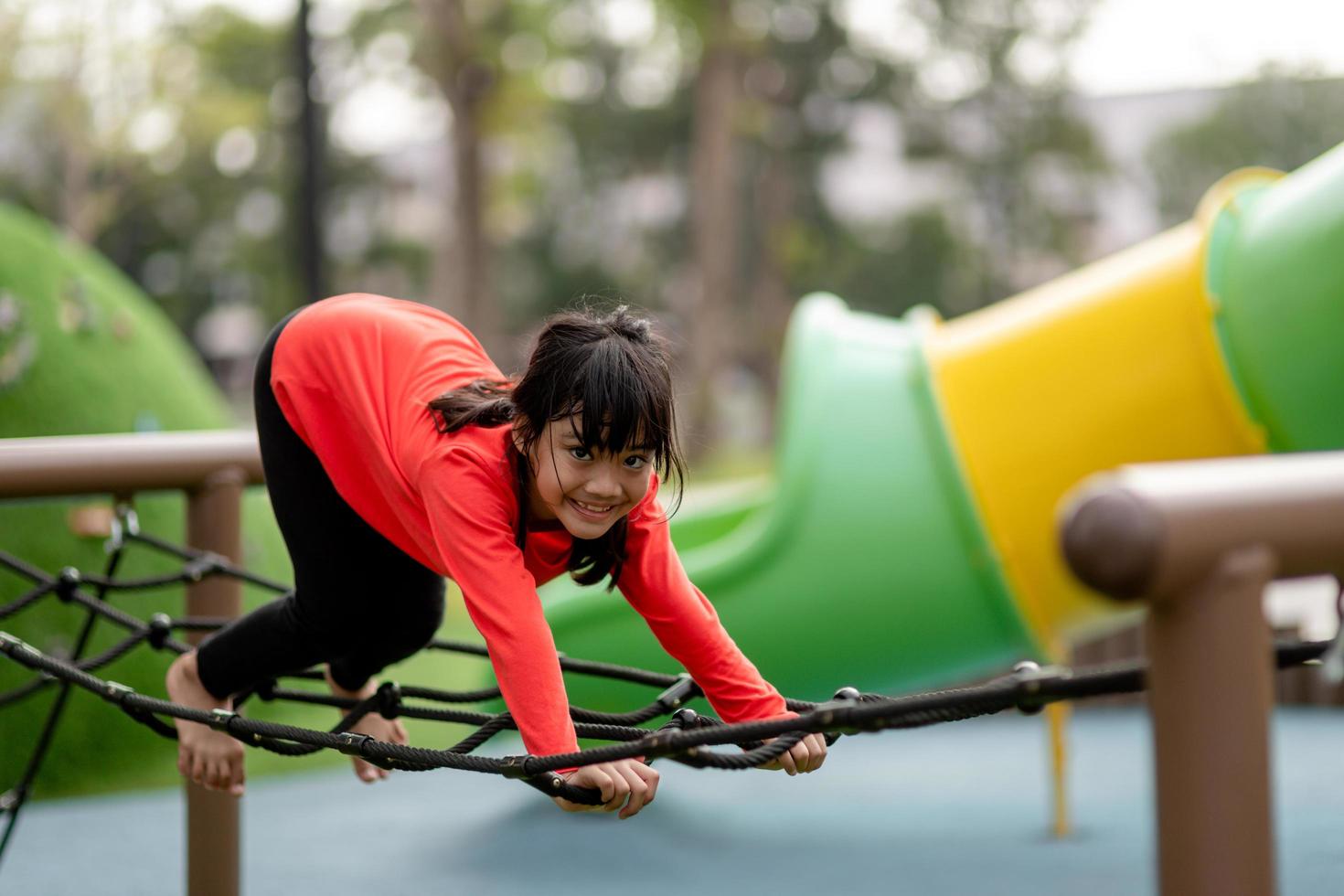Aziatisch meisje speelt graag in een kinderspeeltuin, buitenportret foto