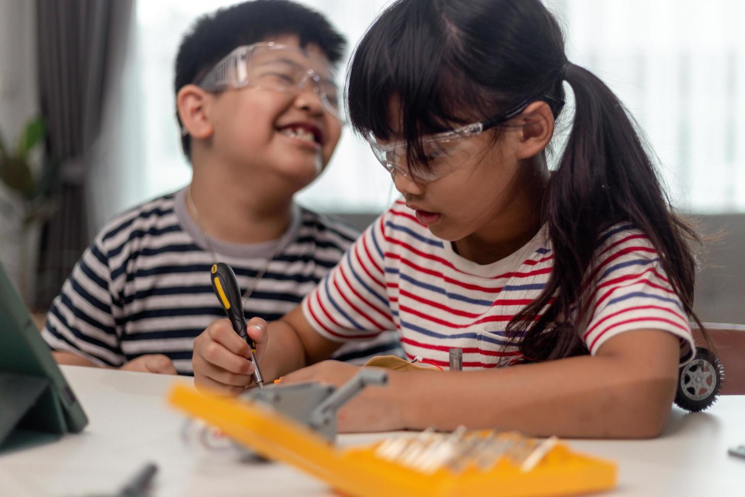 twee aziatische kinderen die plezier hebben samen leren coderen, thuis op afstand leren, stamwetenschap, thuisonderwijs, leuke sociale afstand, isolatie, nieuw normaal concept foto