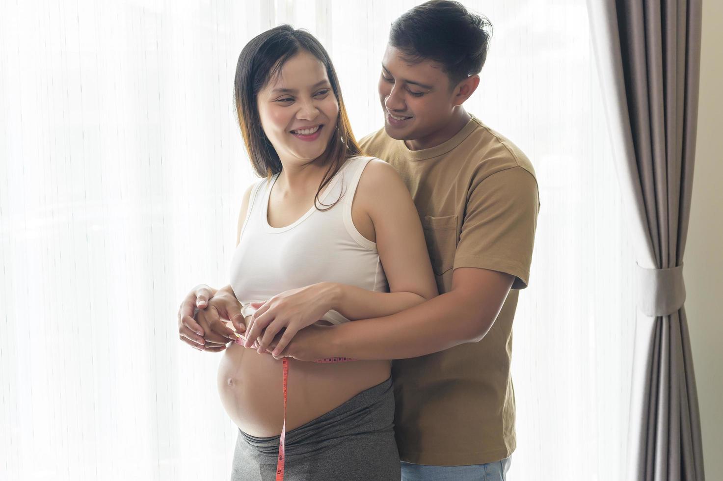 jonge zwangere vrouw die buikcentimeter meet, gezondheidszorg en zwangerschapszorg foto
