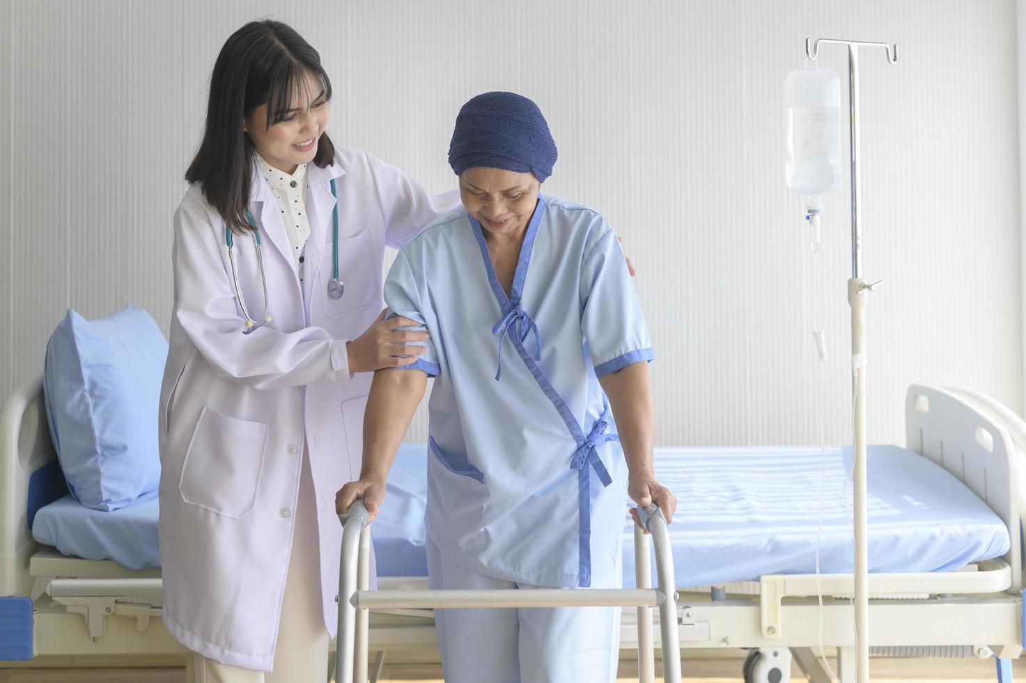 arts die kankerpatiënt vrouw helpt met hoofddoek met rollator in ziekenhuis, gezondheidszorg en medisch concept foto