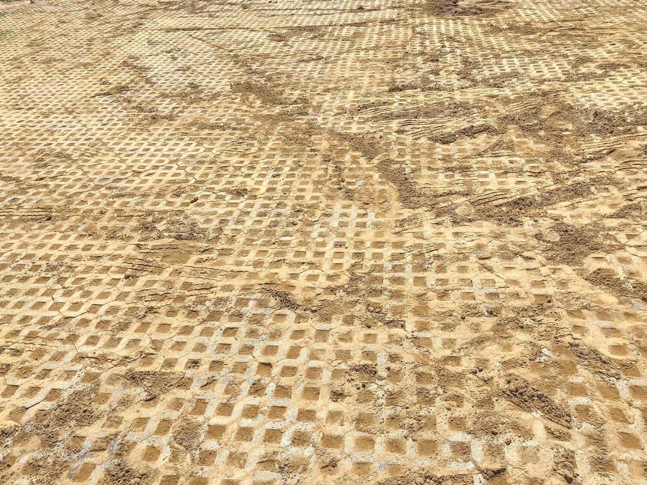 grijze kleur steen baksteen blok vloertegel met groen gras en zand als achtergrond of textuur. foto