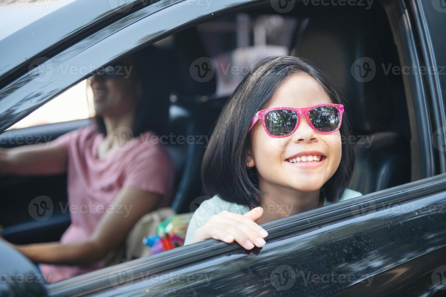 familie vakantie vakantie, gelukkig gezin op een road trip in hun auto, moeder auto rijden terwijl haar dochter naast zit, moeder en dochter reizen. zomerrit met de auto. foto